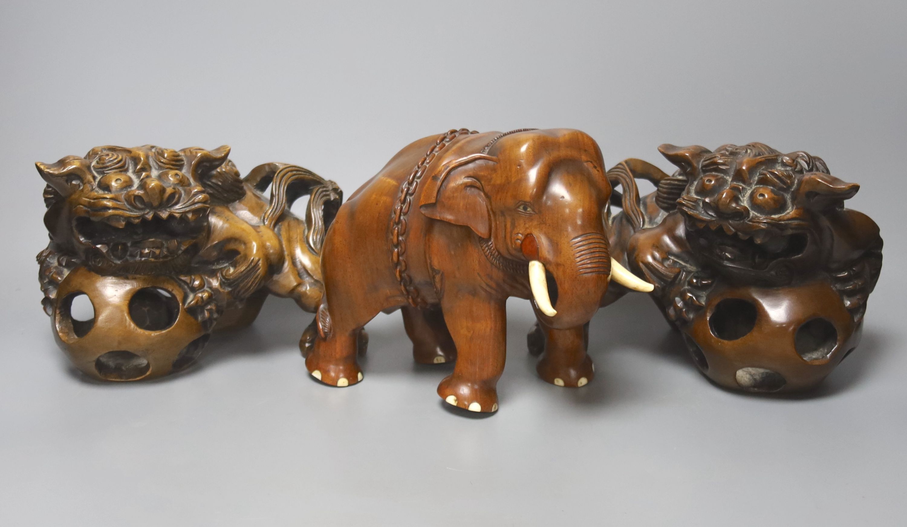 An Indian padouk wood figure of an elephant and a pair of wood figures of Buddhist lions 17cm